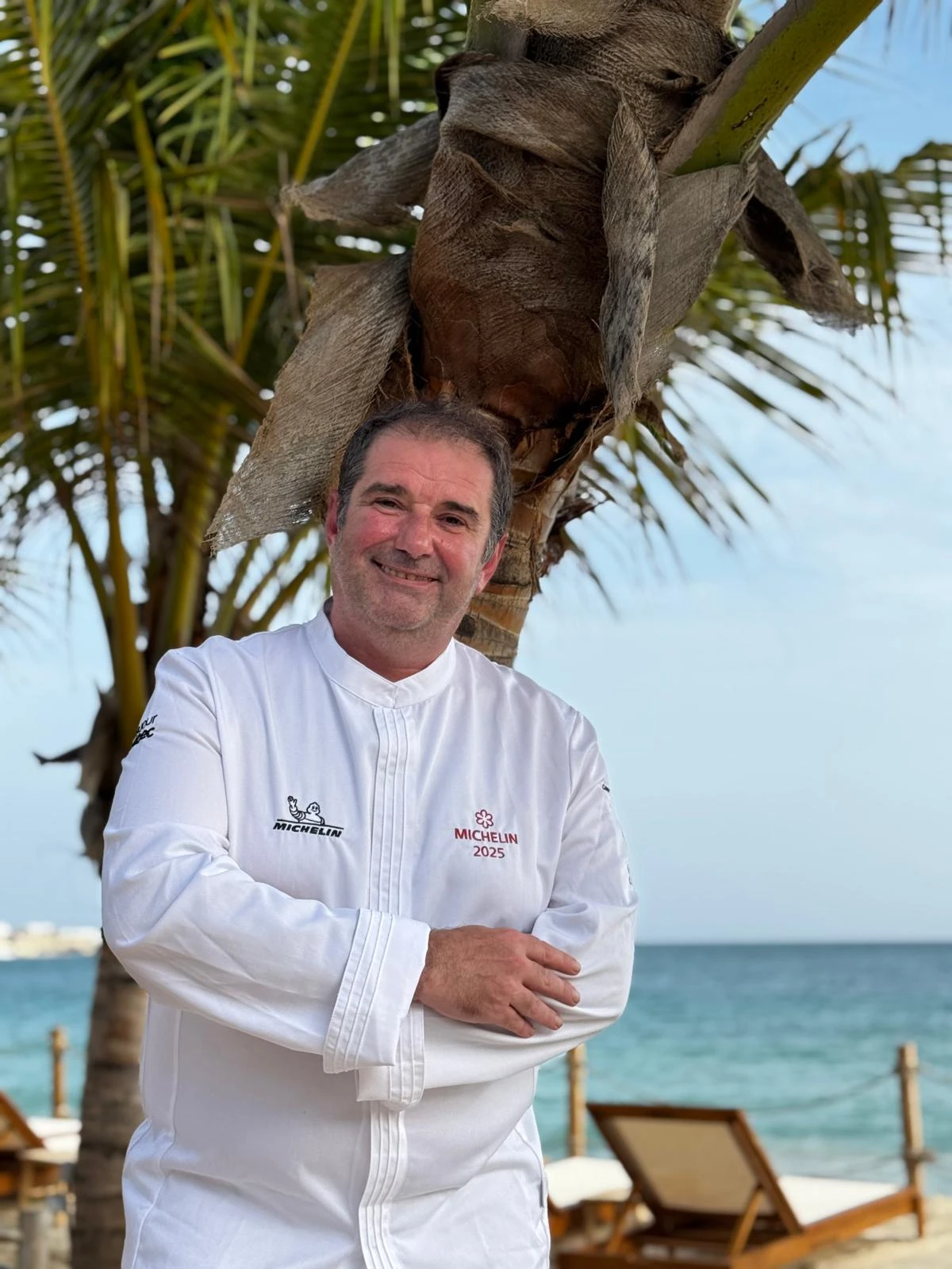 Chef Jérôme Ferrer at the beach beneath a palm tree